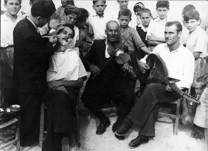 Φωτογραφία του 1950 που απεικονίζει το ξύρισμα του γαμπρού, υπό τη συνοδεία βιολιού και λαούτου. ΛΕΒΕΝΤΕΙΟ ΜΟΥΣΕΙΟ